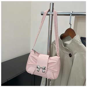 Détail du sac à bandoulière rose clair avec un grand nœud et un charm papillon en argent