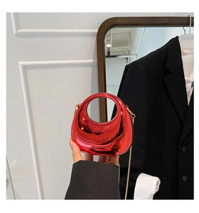 Detail of trendy metallic red dumpling bag with elegant gold chain shoulder strap