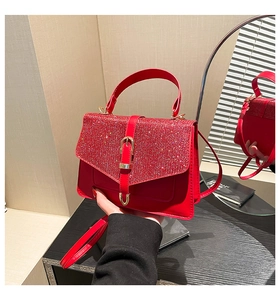 Detail der roten Paillettenhandtasche mit Metallverschluss auf dunklem Holztisch mit Glanz
