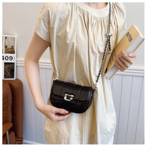 Detail of black quilted leather crossbody bag featuring a silver C-shaped metal buckle