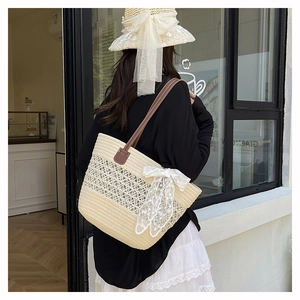 Detail of hollow woven tote bag with brown leather handle and white lace bow accessory