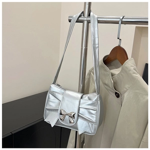 Vue détaillée d'un sac à épaule argenté en forme de nœud avec une boucle métallique