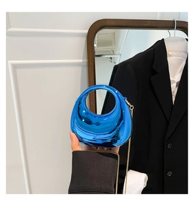 Detail of glossy metallic electric blue crossbody bag with circular cutout handle and gold chain
