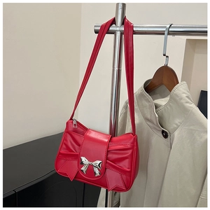 Détail d'un sac à bandoulière rouge avec nœud plissé et boucle métallique argentée sur cintre
