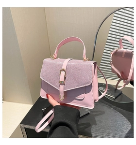 Detail einer rosa Handtasche mit Strassklappe und goldener Magnetschließe auf Holz