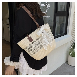 Detail of woven straw tote bag with white lace bow and brown leather shoulder strap