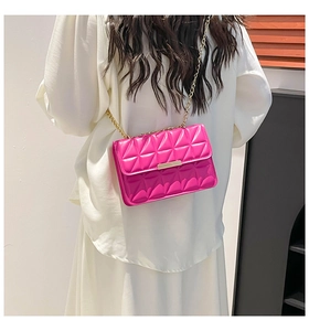 Sac à chaîne matelassé magenta porté à l'épaule sur une tenue blanche minimaliste