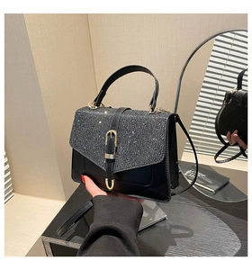 Detail der schwarzen Handtasche mit silberner Glitzerklappe und Goldverschluss