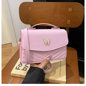 Detail of pink PU leather crossbody bag with butterfly buckle and V-shaped quilting