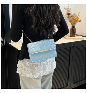 Détail du sac à bandoulière matelassé bleu clair avec chaîne dorée sur un mannequin