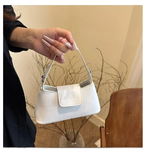 Close-up of white FANYISSA baguette bag featuring smooth PU leather and metal logo detail
