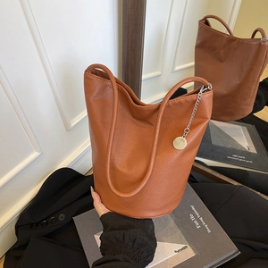 Brown litchi grain soft leather bucket bag with silver chain charm shown in a lifestyle setting