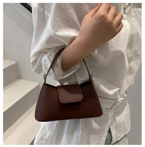 Detail shot of a dark brown minimalist leather handbag with a flap and top handle