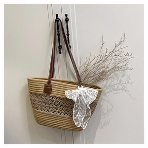 Macro shot of straw tote bag with lace bow, hollow weave detail and brown leather strap
