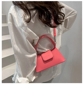 Detail of a bright pink leather shoulder bag with FAMVISSA embossing and silver metal buckle