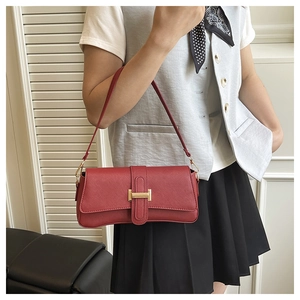 Detail of vintage dark red shoulder bag featuring elegant gold buckle and lychee texture