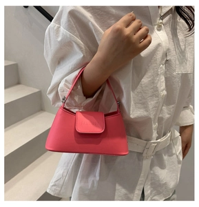Close-up of fuchsia mini square bag featuring a top handle and embossed logo detail