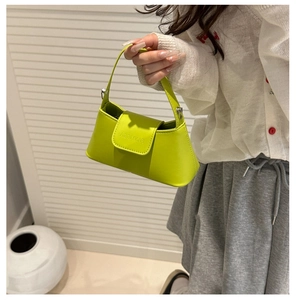 Detail of neon green mini handbag featuring a sleek flap closure and silver metal hardware