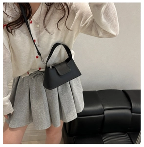 Gros plan du sac en cuir noir mat avec bandoulière réglable et détails en relief