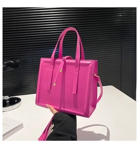 Détail d'un sac à main carré rose vif avec une finition brillante et des détails dorés