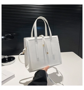 Gros plan du sac cabas en cuir blanc avec détails dorés et cordon de serrage décoratif