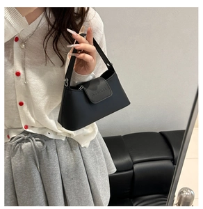 Detail of matte black leather handbag with embossed letters and a semi-circular design