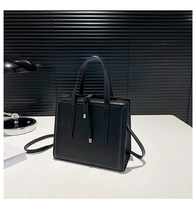 Sac fourre-tout noir structuré minimaliste avec boucle en métal sur une surface moderne