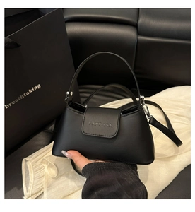 Close-up of minimalist black trapezoid handbag with FANYISSA logo and slender handle