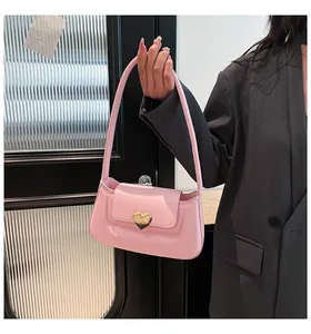 Close-up of pink leather underarm bag with a central gold heart-shaped metallic clasp