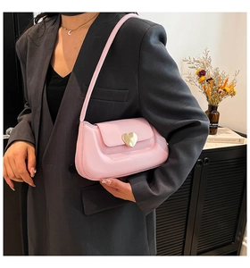 Detailed shot of a pink leather shoulder bag featuring a gold heart-shaped metal buckle