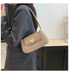 Détail d'un sac sous le bras en cuir mat beige avec une boucle dorée en forme de cœur