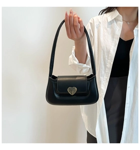 Detail view of a black mini underarm bag featuring a golden heart-shaped metal clasp
