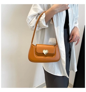 Sac sous le bras en cuir marron avec fermoir cœur argenté porté par un mannequin