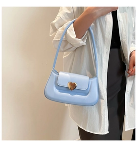 Detail of baby blue leather underarm bag with gold heart-shaped metal lock decoration