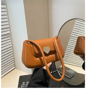 Détail du sac sous le bras en cuir caramel avec un fermoir en métal en forme de cœur