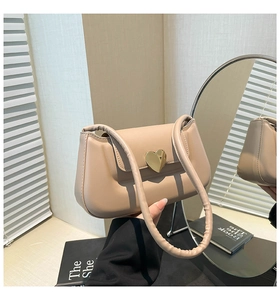 Vue détaillée du fermoir cœur doré sur un sac en cuir texturé beige élégant