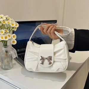 French style white pleated underarm bag with silver bow buckle on office desk