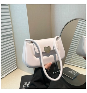 Détail de la boucle cœur dorée sur un sac à bandoulière rose pâle matelassé