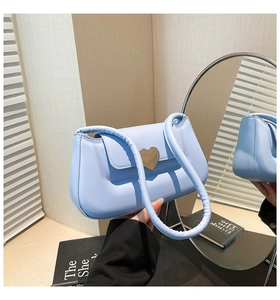 Détail du sac à main bleu clair brillant avec boucle cœur dorée et anse ronde élégante