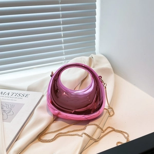 Metallic pink hobo bag with glossy mirror finish and gold chain strap in sunlight