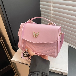 Pink crossbody bag with white butterfly hardware and V-quilted faux leather finish