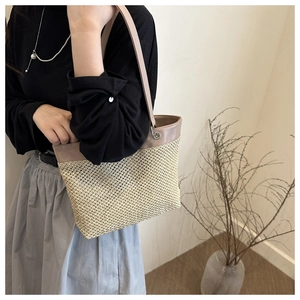 Detailed view of large straw tote bag with brown leather straps for summer beach