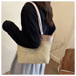 Straw tote bag detail with contrasting leather strap and delicate woven texture closeup