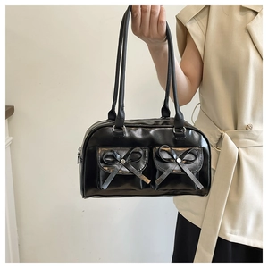 Detail of black bow shoulder bag with silver rivets and sleek glossy finish