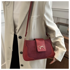 Close-up of burgundy baguette bag with a gold bow buckle and mixed leather textures
