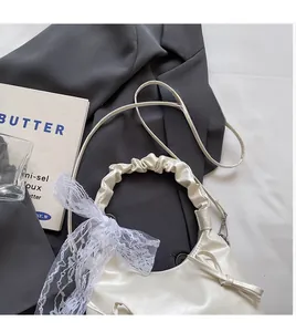 Détail du sac bandoulière blanc crème avec nœuds et bandoulière en dentelle élégante
