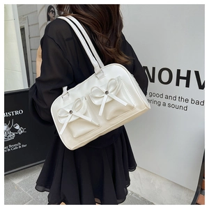 Detail of white bow-adorned pockets and leather texture on a Boston handbag