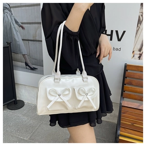 Close-up of white faux leather shoulder bag featuring 3D bow accents and front flap pockets