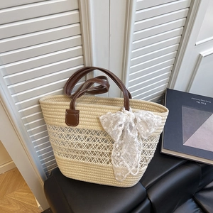 Large woven straw tote bag with brown leather handles and decorative lace bow