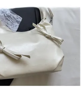 Détail du sac à main en similicuir blanc crème avec texture souple et nœud décoratif